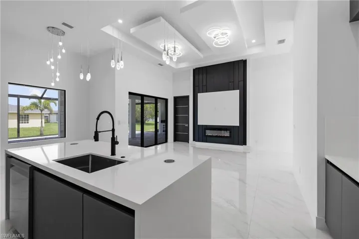 Kitchen with modern cabinets, light marble finish floors, light countertops, a towering ceiling, and recessed lighting
