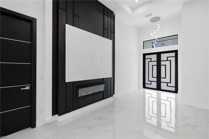 Corridor featuring light marble finish flooring, a towering ceiling, and a tray ceiling