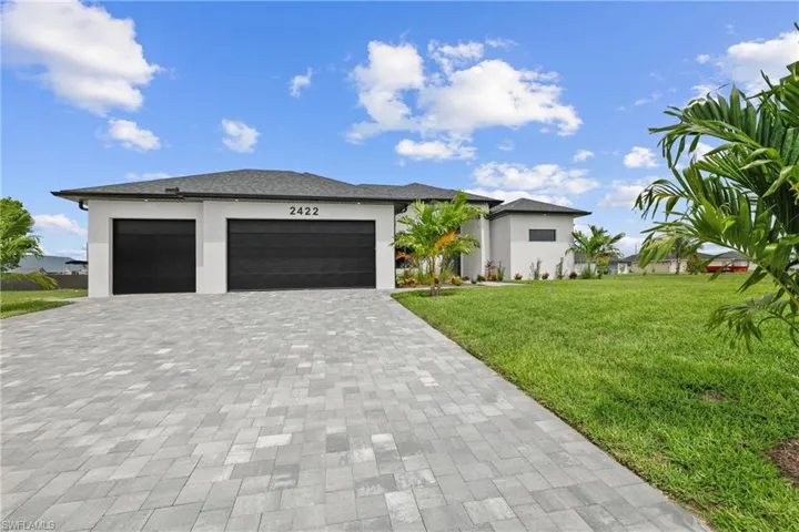 Prairie-style home with decorative driveway, a front yard, stucco siding, and a garage