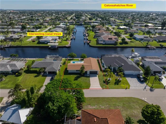Waterfront property featuring a concrete seawall, private swimming pool, concrete driveway, and direct access to an intersecting canal system