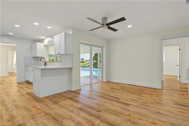 Kitchen featuring white cabinetry, solid-surface countertops, and a subway tile backsplash, complemented by wood-finish flooring, recessed lighting, and a ceiling fan