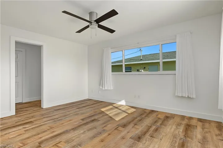 Wood-finish flooring, large multi-pane window, and four-blade ceiling fan with integrated light fixture