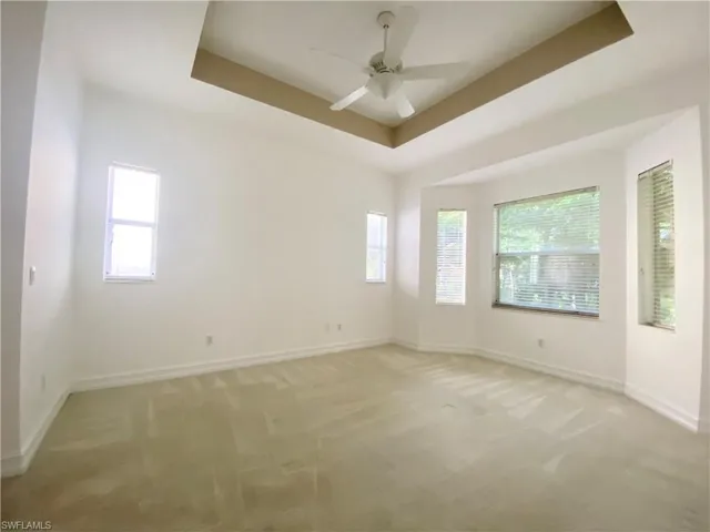 Main bedroom featuring a tray ceiling, tinted windows and ceiling fan