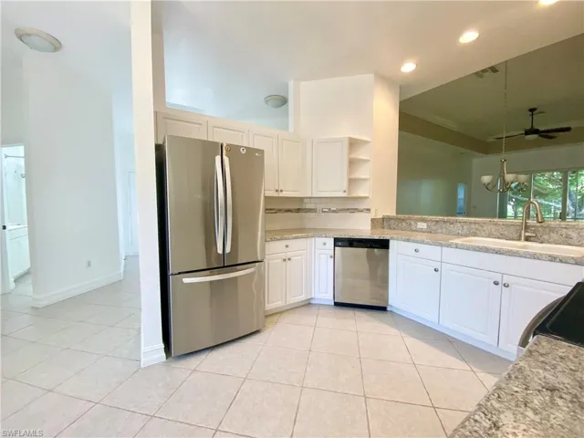 Kitchen featuring white cabinets, sink, stainless steel appliances, and ceiling fan with notable chandelier