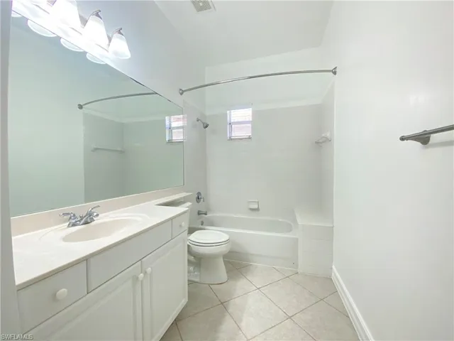 Full bathroom featuring toilet, tile patterned floors, vanity, and tiled shower / bath
