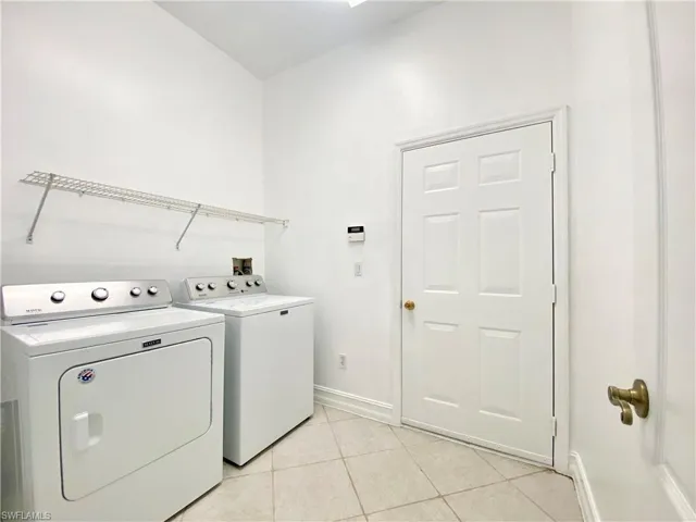 Laundry area featuring light tile patterned floors and washing machine and clothes dryer