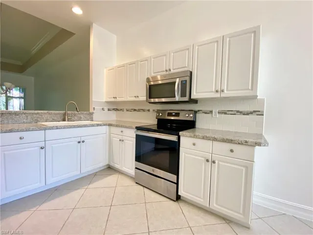 Kitchen featuring appliances with stainless steel finishes, white cabinetry, sink, and backsplash