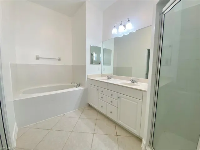 Bathroom featuring tile patterned floors, double sink vanity, and separate shower and tub