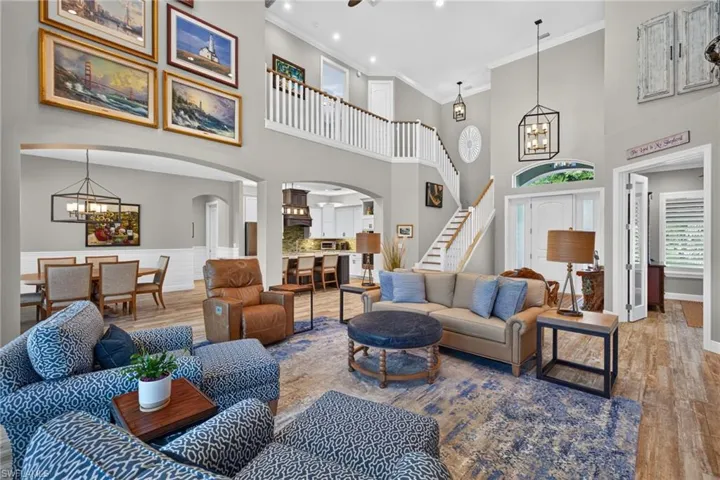 Two-story living area featuring a grand staircase, vaulted ceilings, and wood-finish flooring