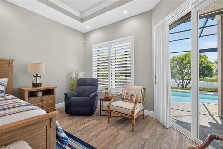Primary Bedroom featuring wood-finish flooring, a tray ceiling, and recessed lighting
