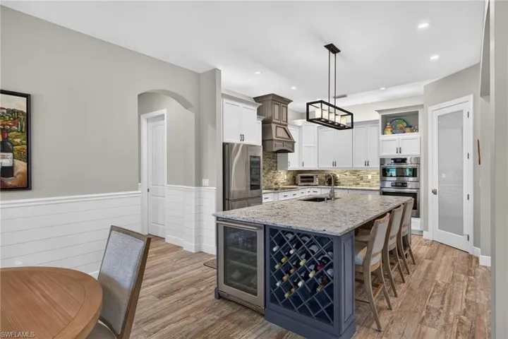 Spacious kitchen featuring an expansive center island with seating, integrated wine storage, and a built-in beverage cooler