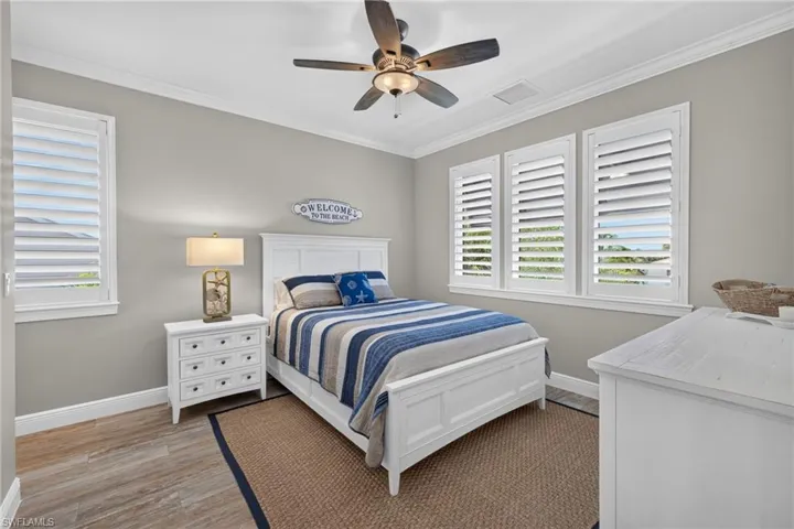 Interior room featuring wood-finish flooring, white crown molding, and a ceiling fan with light fixture
