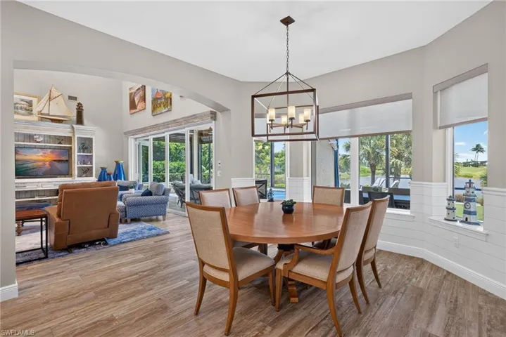 Dining area featuring a wood-finish flooring, a contemporary chandelier, and shiplap wainscoting