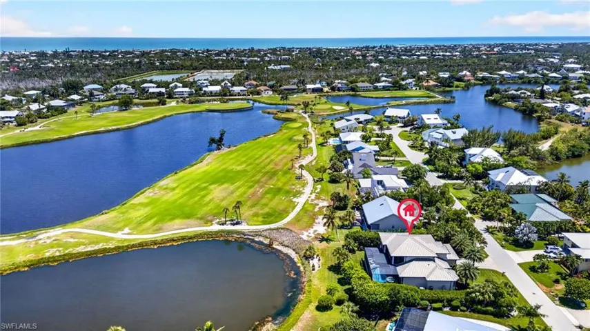 Aerial perspective showcasing a residential property with a multi-level roofline, surrounded by lush landscaping