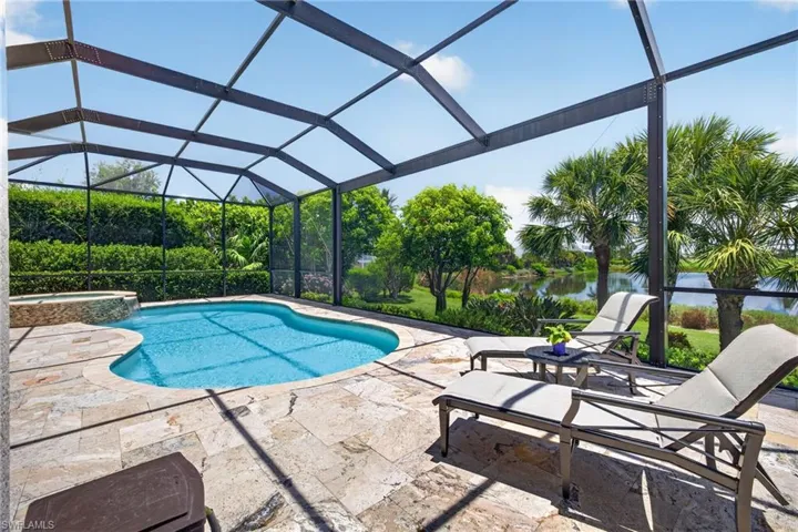 Screened outdoor area featuring a freeform swimming pool and integrated spa with stone surround