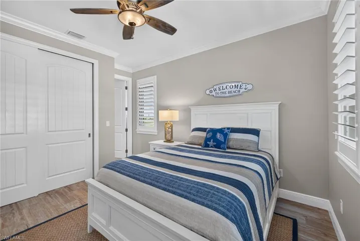 Neutral-toned bedroom featuring wood-finish flooring and crown molding