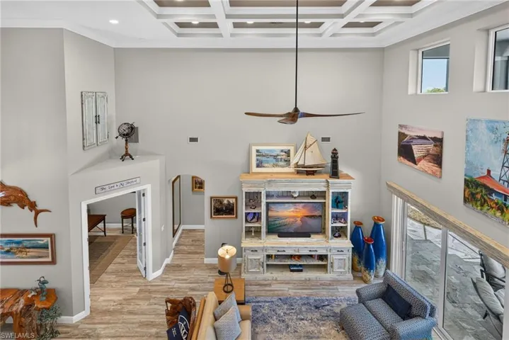 Soaring living space featuring wood-finish flooring and a coffered ceiling with recessed lighting