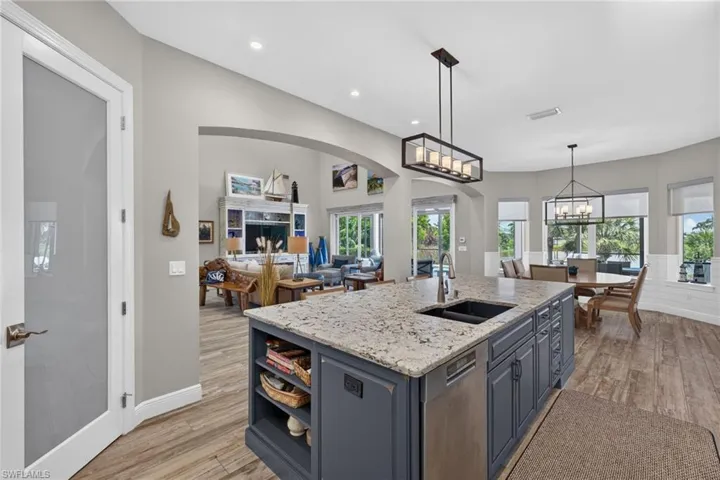 Spacious kitchen island featuring a granite countertop, built-in sink, and stainless steel dishwasher