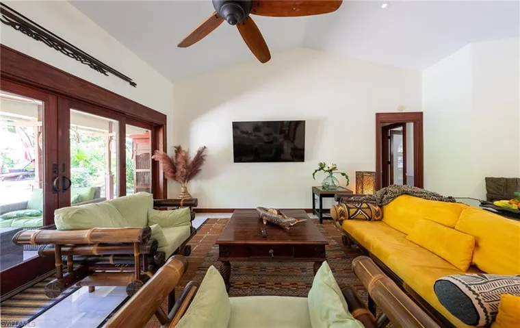 Living room featuring vaulted ceiling, french doors, ceiling fan, and baseboards