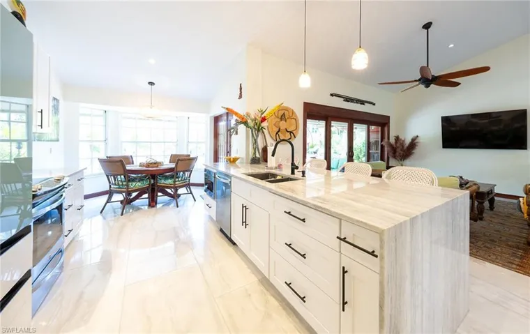 Kitchen featuring a sink, healthy amount of natural light, light stone counters, appliances with stainless steel finishes, and lofted ceiling