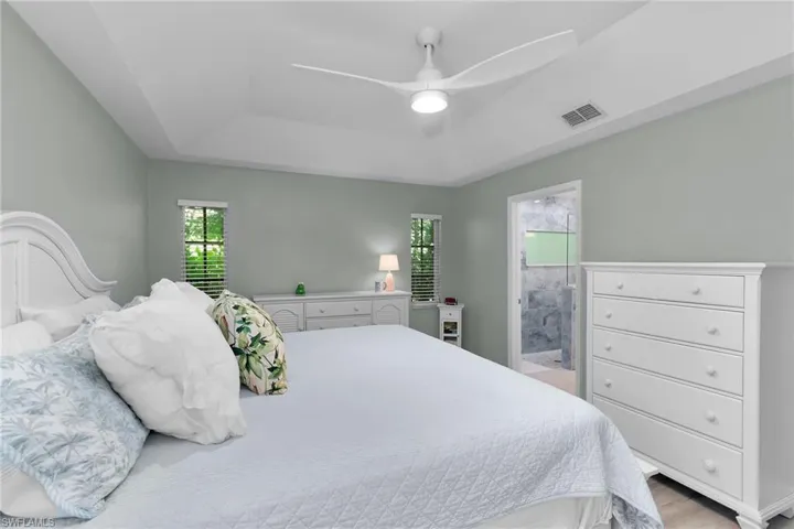 Bedroom with a ceiling fan, a tray ceiling, and light wood-type flooring