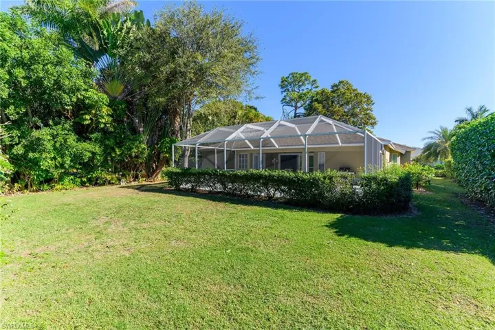 Back of house featuring glass enclosure, a sunroom, and a lawn