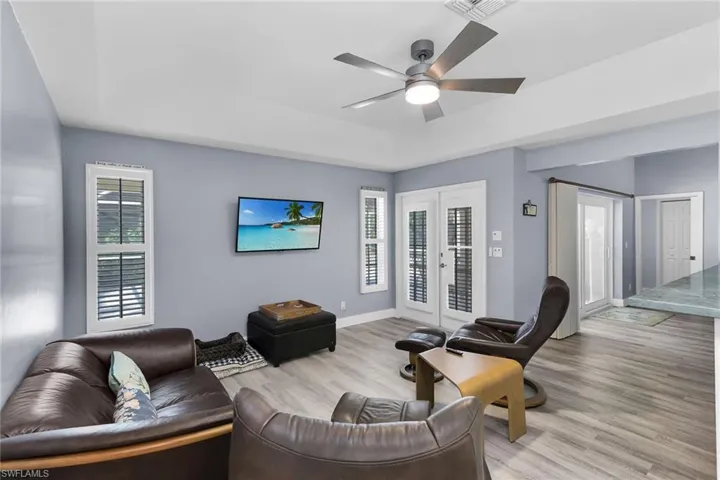 Living area featuring healthy amount of natural light, wood finished floors, a ceiling fan, and a tray ceiling