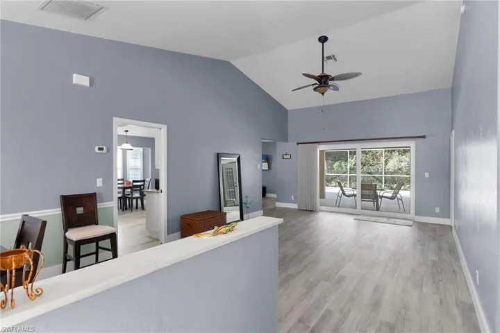Living room featuring plenty of natural light, ceiling fan, light wood-style floors, and high vaulted ceiling