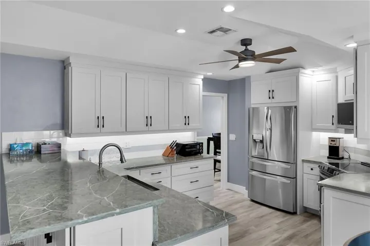 Kitchen featuring appliances with stainless steel finishes, a peninsula, white cabinets, and recessed lighting