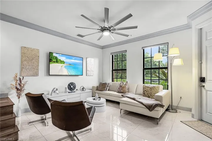 Living area with crown molding, marble finish flooring, and ceiling fan
