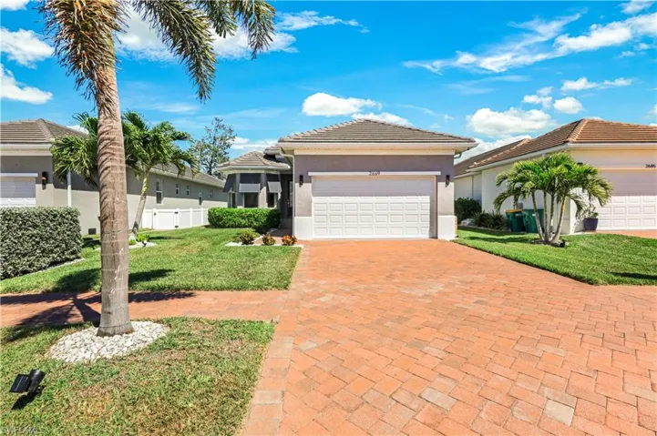 View of front of home with driveway, a tile roof, stucco siding and a 2 car garage.