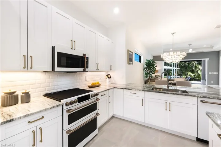 Kitchen with white GE Cafe appliances, tasteful backsplash, a SS farmers sink, and upgraded white Shaker style cabinets.