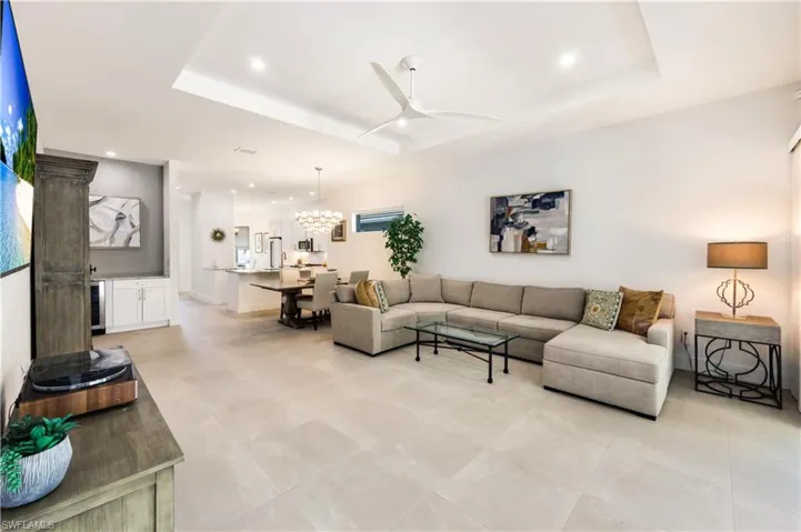 Open floor plan living area with recessed lighting and view of the dining area and kitchen.
