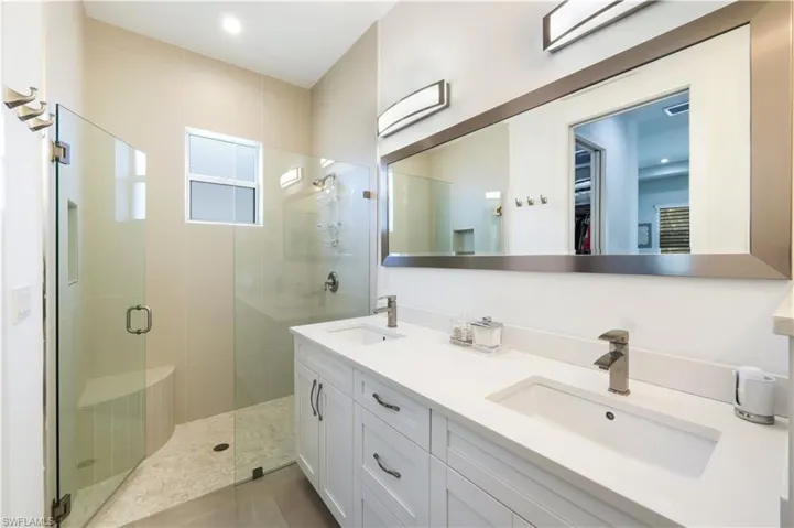 Primary Bathroom featuring double vanity sinks and a stall shower.