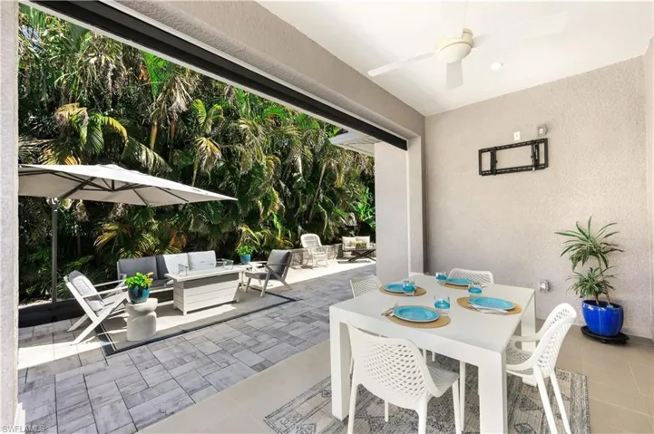 View of back lanai featuring an outdoor living space, outdoor dining area and motorized roll down screens. Perfect for bug free entertaining.