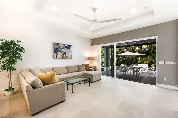 Living room with ceiling fan, and a raised ceiling. 24" tile floors throughout.