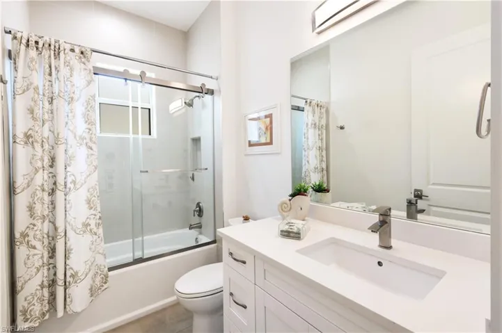 Full bath featuring enclosed tub / shower combo, toilet, and vanity