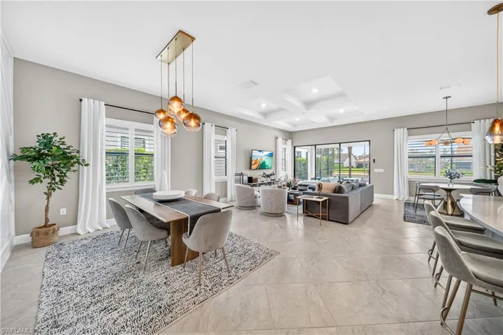 Spacious open-concept interior featuring light tile flooring throughout, a coffered ceiling, and large sliding glass doors providing abundant natural light
