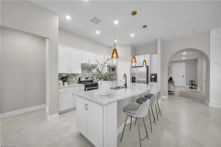Kitchen featuring a large island with a quartz countertop, white cabinetry, integrated stainless steel appliances, and tile flooring