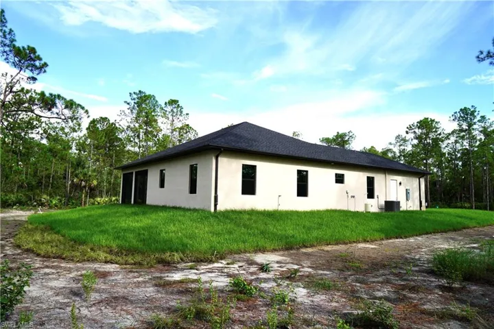 View of side of home with stucco siding and a lawn