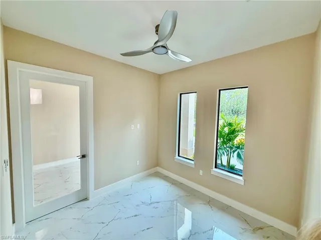 Empty room featuring light marble finish floors and ceiling fan