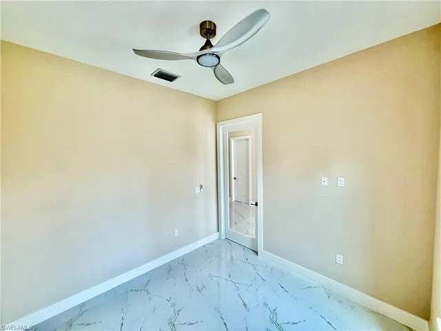 Spare room featuring marble look tile flooring and a ceiling fan