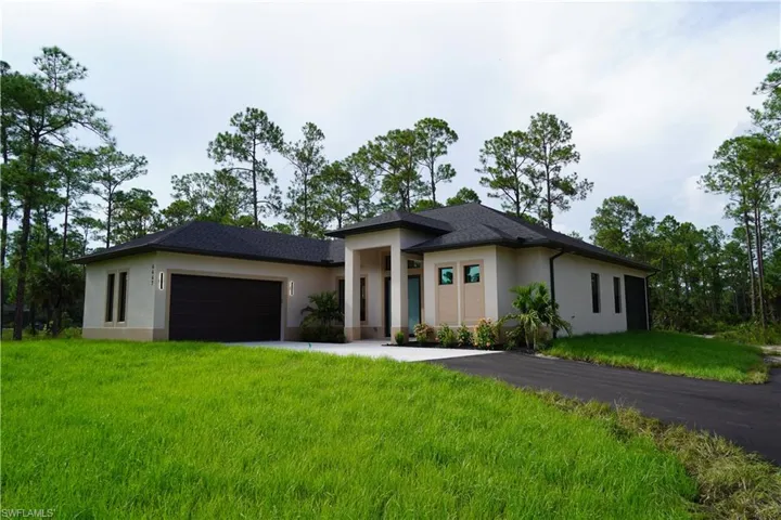Prairie-style house with stucco siding, a front yard, driveway, and an attached garage