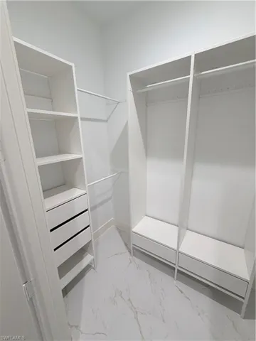 Walk in closet with light marble finish flooring