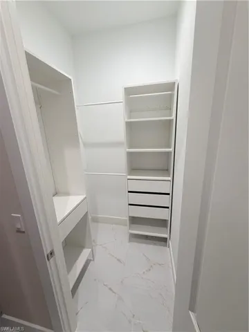 Walk in closet featuring light marble finish flooring