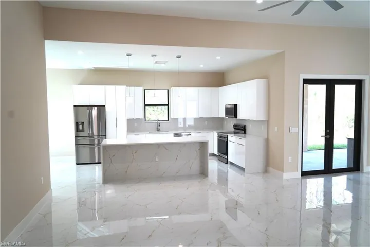 Kitchen featuring appliances with stainless steel finishes, decorative light fixtures, white cabinets, decorative backsplash, and light stone countertops