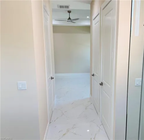Hall featuring light marble finish flooring and recessed lighting