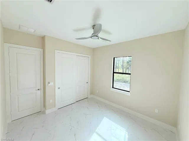 Unfurnished bedroom featuring light marble finish floors, a closet, and ceiling fan
