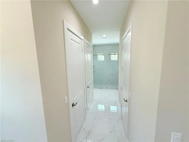 Corridor featuring light marble finish floors and recessed lighting