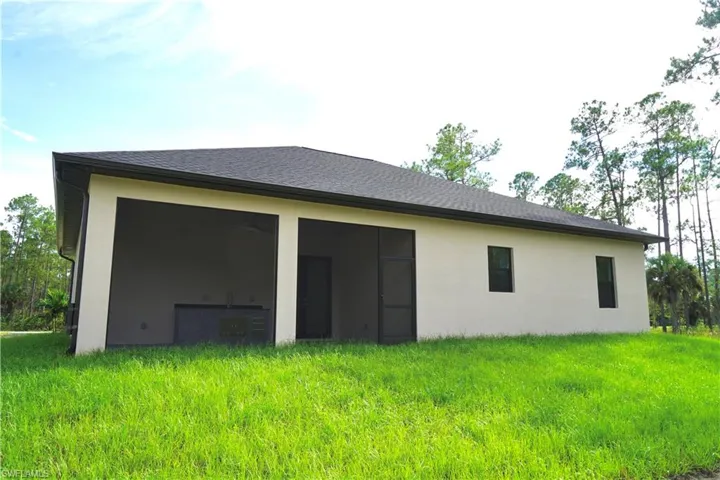 Back of property featuring stucco siding, a yard, a sunroom, and a shingled roof